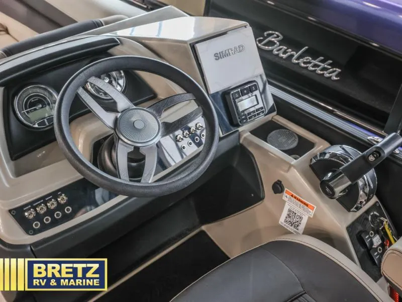 Slide: The Image of 2023 Cabrio 24UC boat dashboard with steering wheel and controls, featuring Simrad electronics. - 12