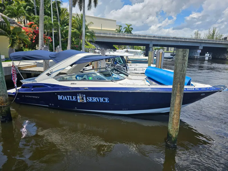 Slide: The Image of 2012 Monterey 328SS Super Sport boat docked by a riverside with blue canopy. - 2
