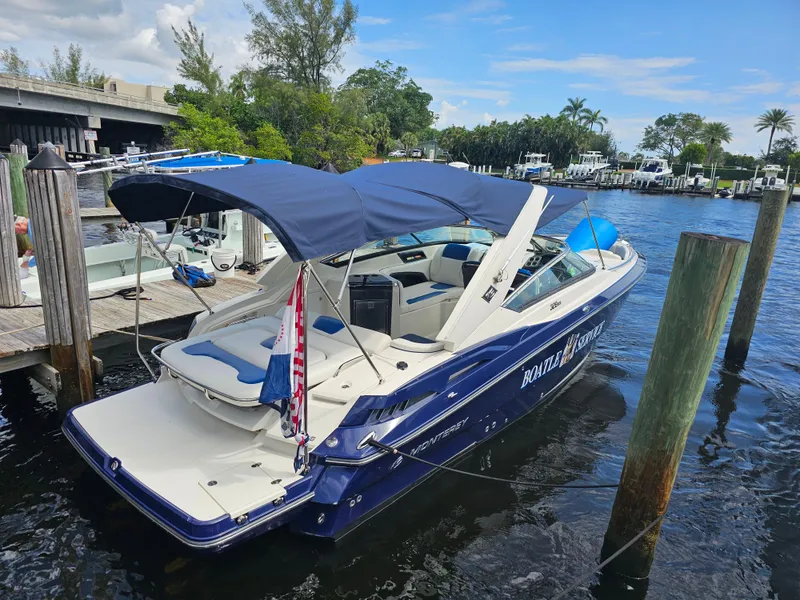 Slide: The Image of 2012 Monterey 328SS Super Sport boat docked with blue canopy and American flag. - 6