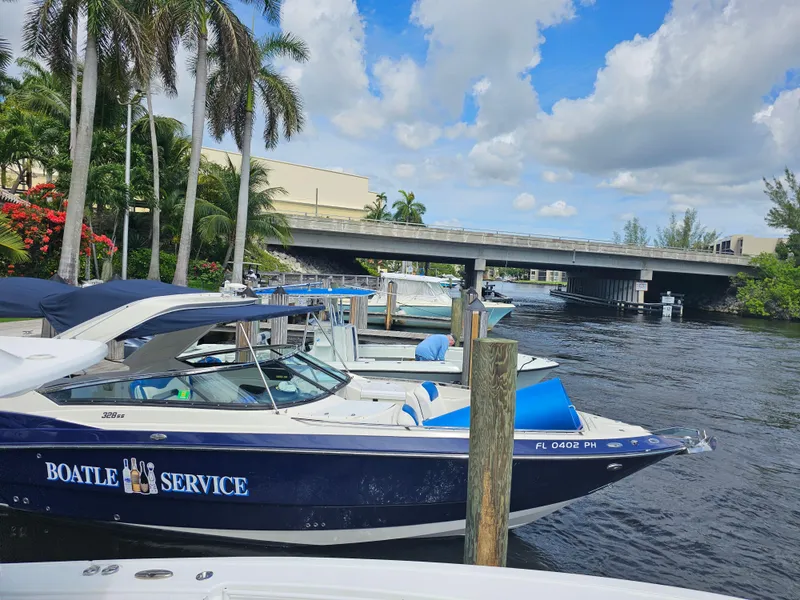 Slide: The Image of 2012 Monterey 328SS Super Sport boat docked near a bridge, surrounded by palm trees. - 7