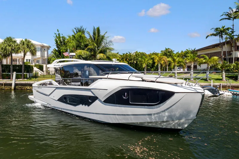 Slide: The Image of 2022 Absolute 48 Coupe yacht cruising on a sunny day, surrounded by palm trees. - 1