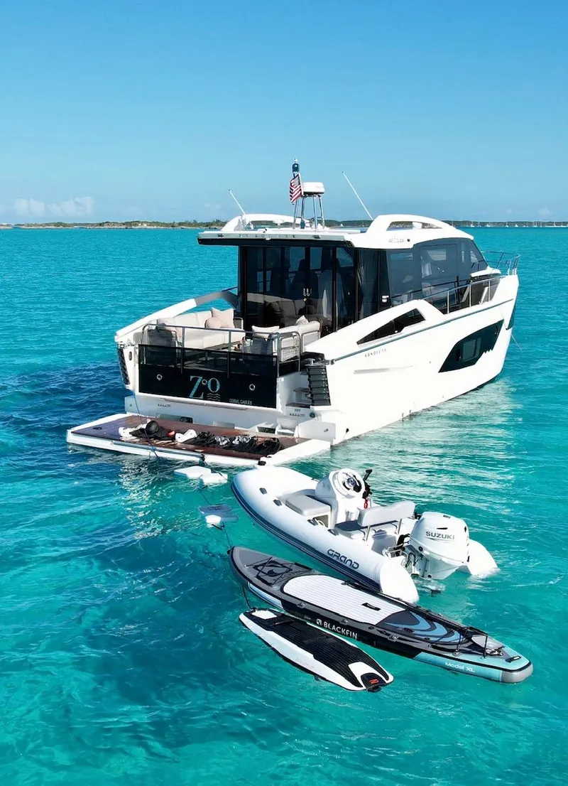 Slide: The Image of 2022 Absolute 48 Coupe yacht on turquoise water with paddleboards and inflatable boat. - 8