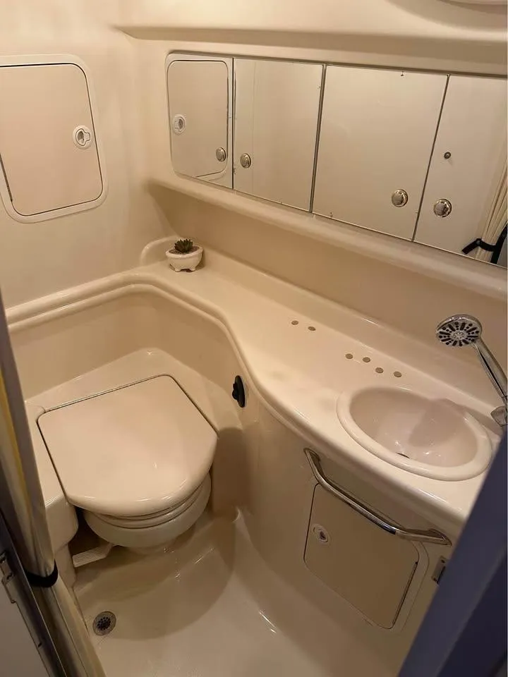 Slide: The Image of 2003 Sea Ray 320 Sundancer bathroom with toilet, sink, and storage cabinets. - 3