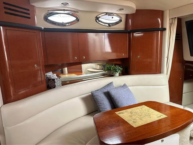 Slide: The Image of 2003 Sea Ray 320 Sundancer interior with wood cabinets, plush seating, and a cozy dining area. - 8