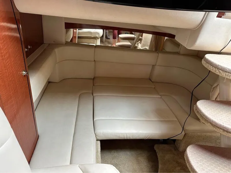 Slide: The Image of 2003 Sea Ray 320 Sundancer interior with beige seating and wooden cabinetry. - 9