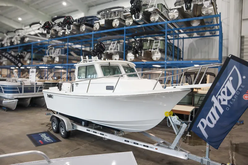 The Image of 2025 Parker 2120 Sport Cabin boat on trailer in showroom with Parker flag. - 0