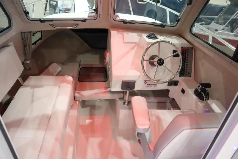 Slide: The Image of Interior of 2025 Parker 2120 Sport Cabin boat, featuring steering wheel and seating area. - 10