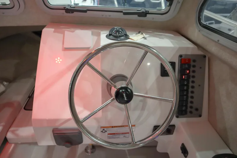 Slide: The Image of Steering wheel of 2025 Parker 2120 Sport Cabin boat, featuring control panel and compass. - 13