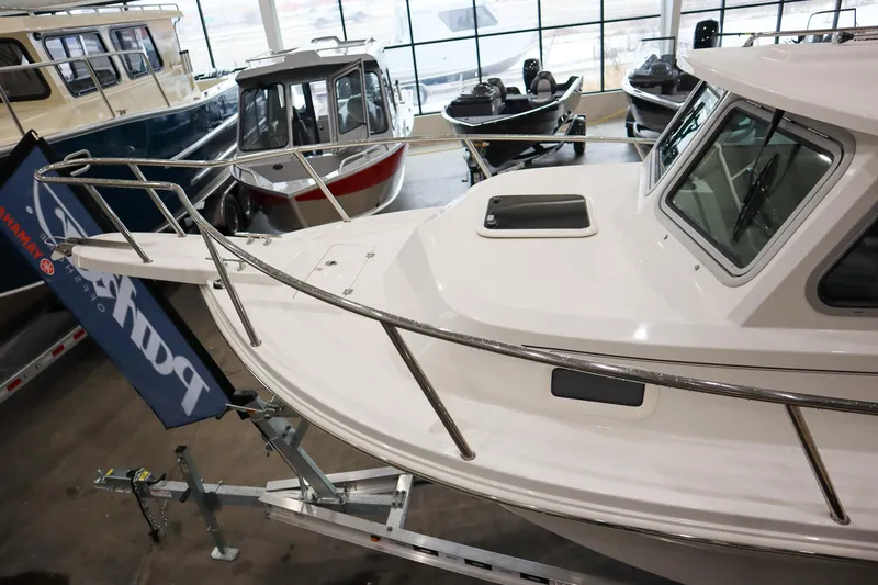 Slide: The Image of 2025 Parker 2120 Sport Cabin boat displayed indoors, surrounded by other boats. - 16