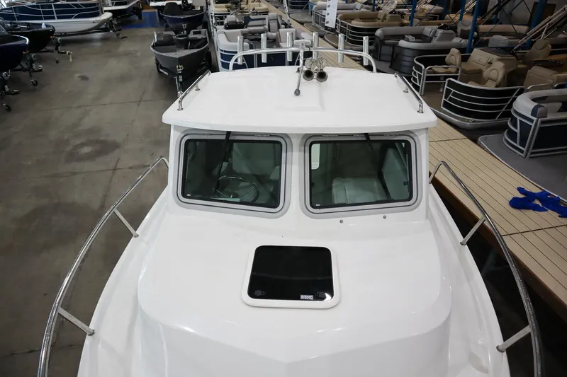 Slide: The Image of 2025 Parker 2120 Sport Cabin boat in a showroom, showcasing its sleek design and cabin windows. - 17