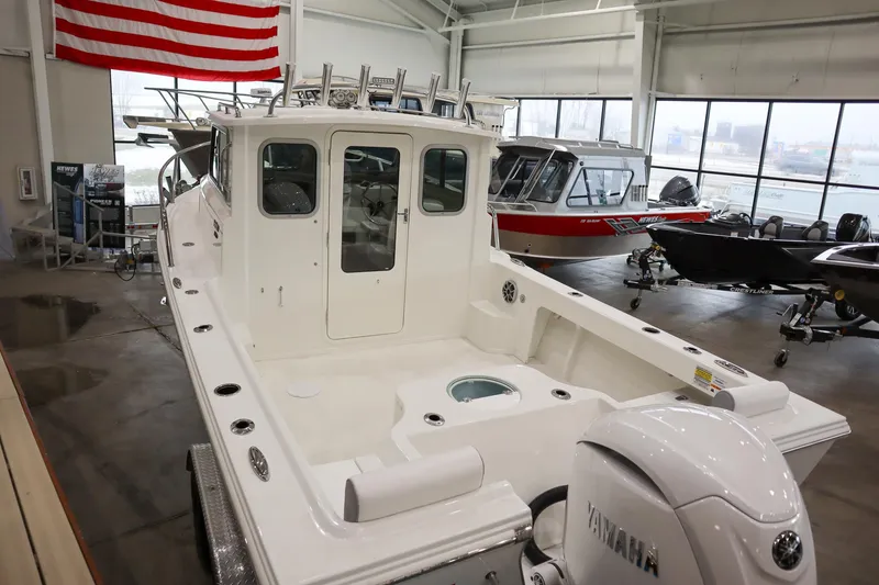 Slide: The Image of 2025 Parker 2120 Sport Cabin boat in showroom, featuring spacious deck and Yamaha engine. - 7