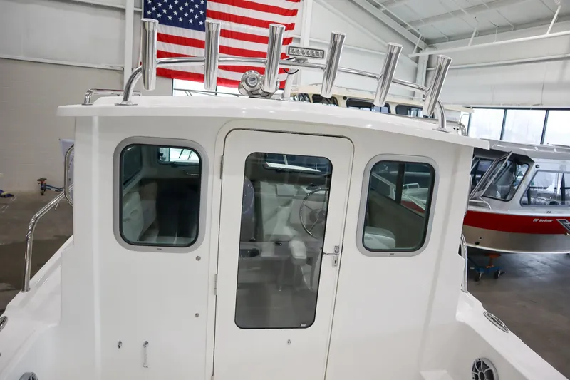 Slide: The Image of 2025 Parker 2120 Sport Cabin boat in showroom with American flag backdrop. - 9