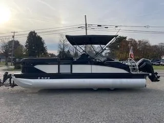 Slide: The Image of 2024 Barletta C22UC pontoon boat parked on a gravel surface, side view. - 3