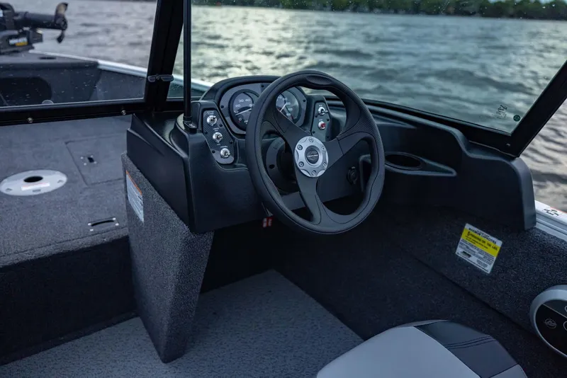 Slide: The Image of 2025 Crestliner 1650 KODIAK WT boat interior with steering wheel and dashboard, on a lake. - 16