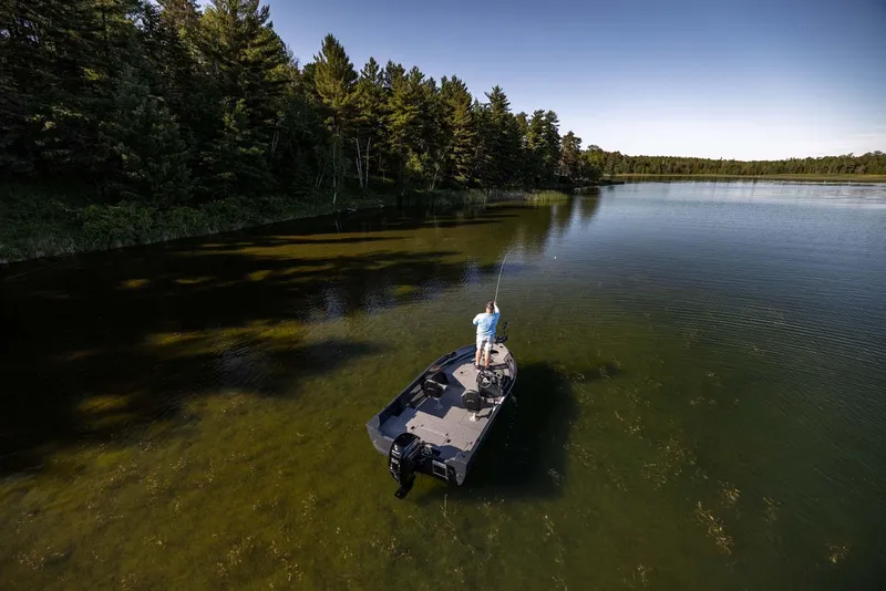 Slide: The Image of 2025 Crestliner 1650 KODIAK WT fishing boat on a serene lake surrounded by trees. - 18