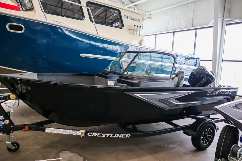 Slide: The Image of 2025 Crestliner 1650 KODIAK WT boat in showroom, black exterior, on trailer. - 2