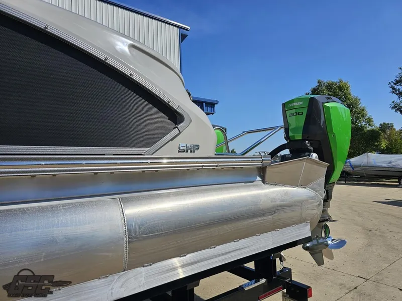 Slide: The Image of 2021 Manitou 25 X-Plode pontoon boat with green outboard motor, parked outdoors. - 18