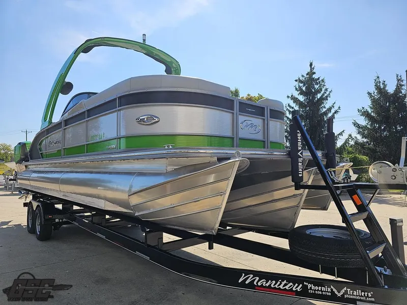 Slide: The Image of 2021 Manitou 25 X-Plode pontoon boat on trailer, featuring sleek design and vibrant green accents. - 22
