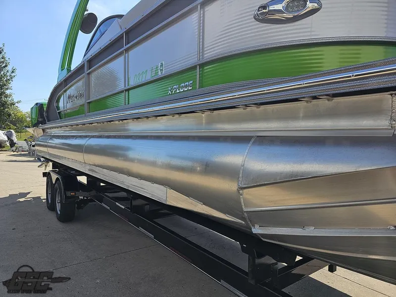 Slide: The Image of 2021 Manitou 25 X-Plode pontoon boat with green accents on a trailer. - 23