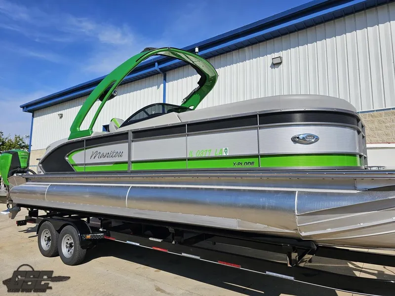 Slide: The Image of 2021 Manitou 25 X-Plode pontoon boat on trailer, green and silver design. - 25