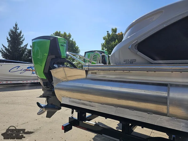 Slide: The Image of 2021 Manitou 25 X-Plode pontoon boat with green outboard motor, parked outdoors. - 33