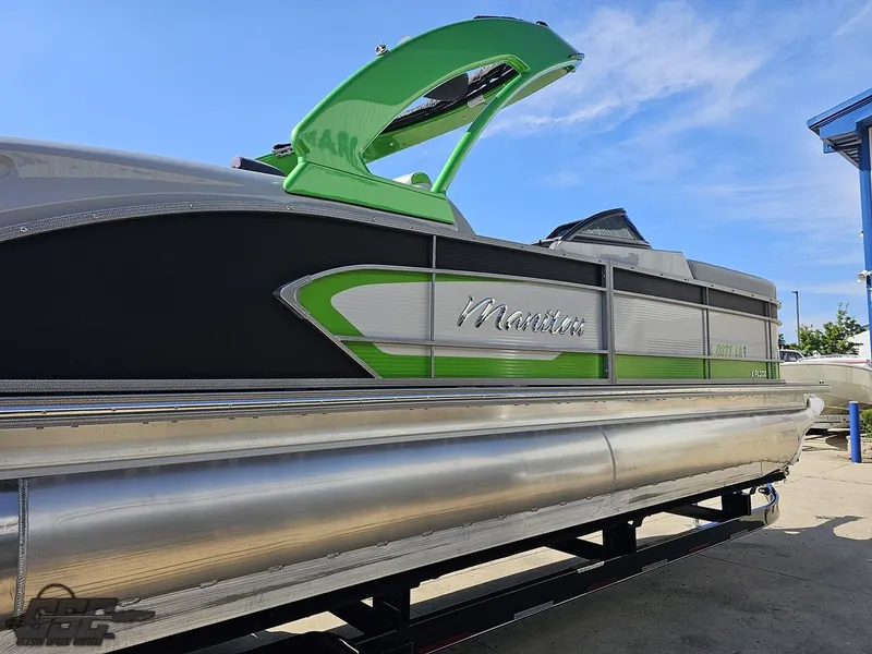 Slide: The Image of 2021 Manitou 25 X-Plode pontoon boat with green accents, docked under a clear sky. - 34