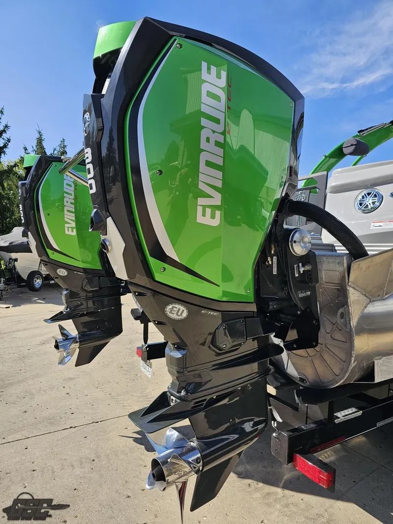 Slide: The Image of 2021 Manitou 25 X-Plode with green Evinrude outboard motors, parked on a sunny day. - 38