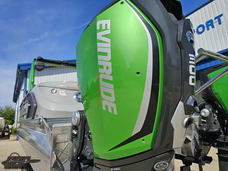 Slide: The Image of 2021 Manitou 25 X-Plode with green Evinrude outboard motor, parked outdoors. - 44
