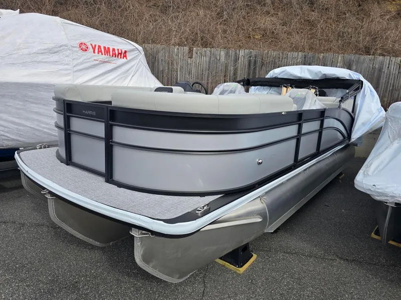 Slide: The Image of 2025 Harris Cruiser 210 pontoon boat in storage, gray exterior, covered nearby. - 19