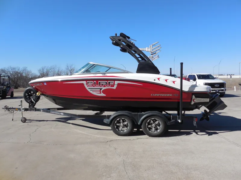 Slide: The Image of 2019 Chaparral 21 H2O Surf boat, red and white, on a trailer in a parking lot. - 5
