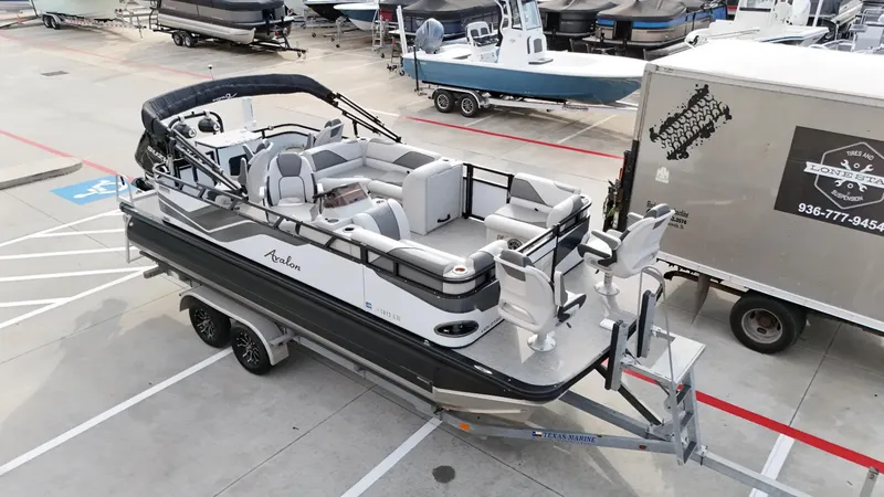 Slide: The Image of 2023 Avalon VEN 2180 FNC pontoon boat on trailer in a marina parking lot. - 10