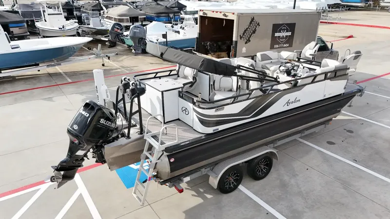 Slide: The Image of 2023 Avalon VEN 2180 FNC pontoon boat on trailer, parked in marina lot. - 11