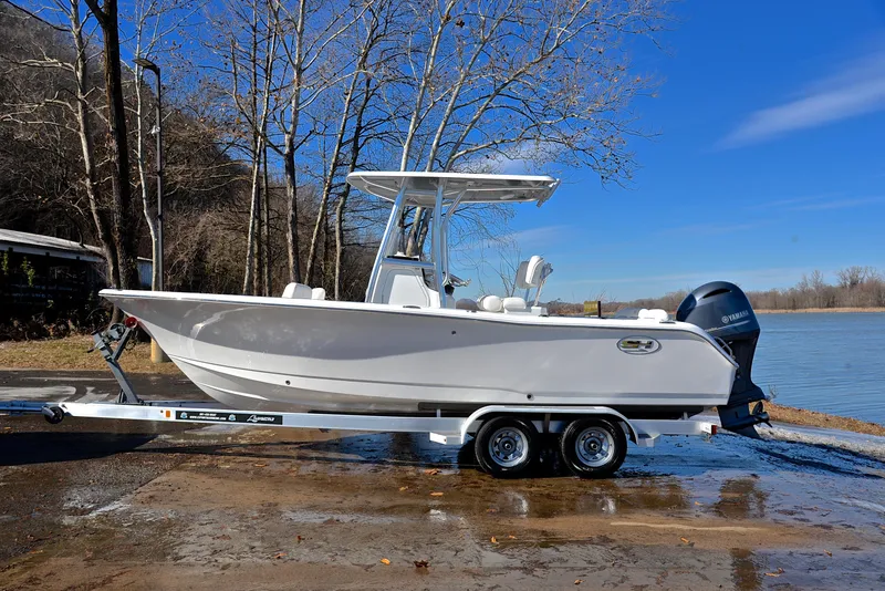 Slide: The Image of 2019 Sea Hunt 225 Ultra boat on trailer by a lake, clear blue sky. - 11