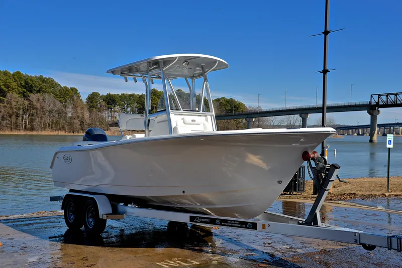 Slide: The Image of 2019 Sea Hunt 225 Ultra boat on trailer by a lake. - 16