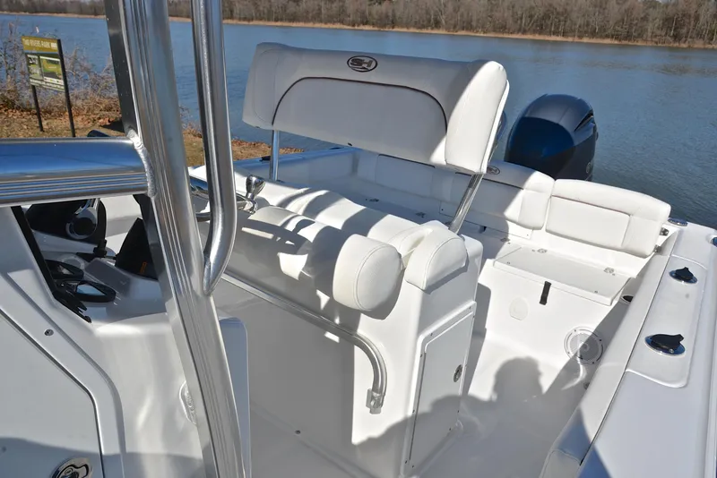 Slide: The Image of 2019 Sea Hunt 225 Ultra boat interior with seating and controls by a lake. - 23
