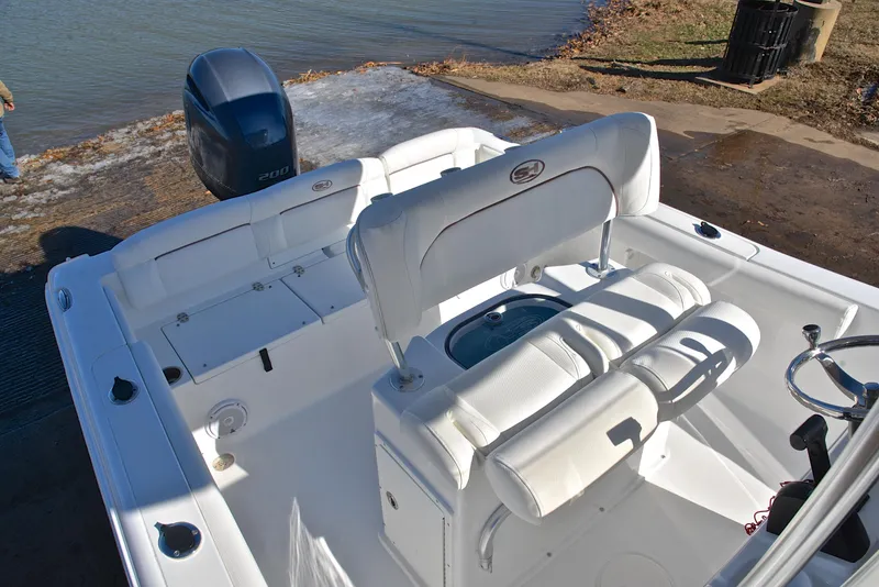 Slide: The Image of 2019 Sea Hunt 225 Ultra boat interior with white seating and outboard motor near water. - 24