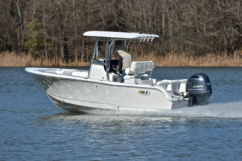 Slide: The Image of 2019 Sea Hunt 225 Ultra boat cruising on a calm lake with trees in the background. - 4