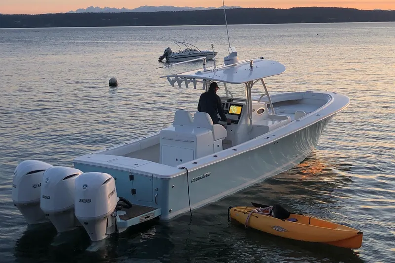 Slide: The Image of 2007 Regulator 34 Center Console boat on calm water at sunset, with kayaks nearby. - 24