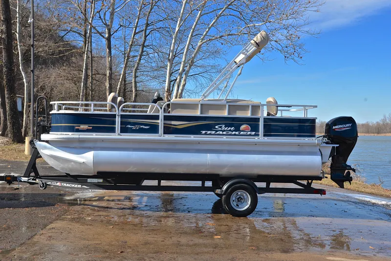 Slide: The Image of 2023 Sun Tracker Bass Buggy 18 DLX pontoon boat on trailer by a lake. - 11