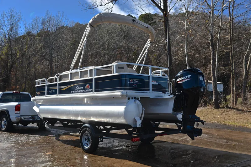 Slide: The Image of 2023 Sun Tracker Bass Buggy 18 DLX pontoon boat on trailer, parked outdoors. - 12