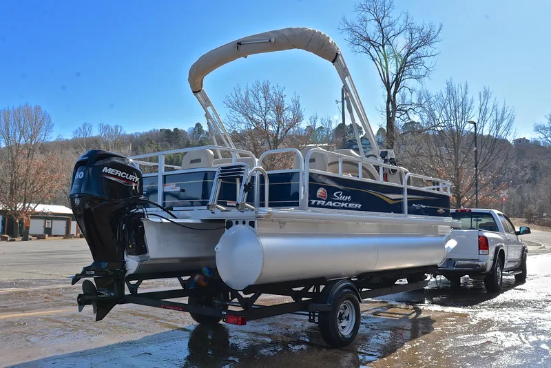 Slide: The Image of 2023 Sun Tracker Bass Buggy 18 DLX pontoon boat on trailer, parked outdoors. - 14