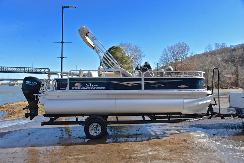 Slide: The Image of 2023 Sun Tracker Bass Buggy 18 DLX pontoon boat on trailer by a river. - 15