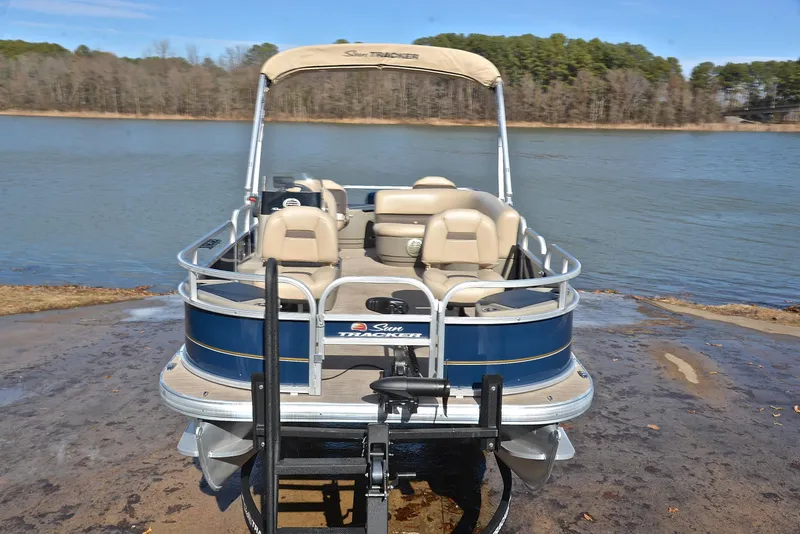 Slide: The Image of 2023 Sun Tracker Bass Buggy 18 DLX pontoon boat on a lake shore. - 17
