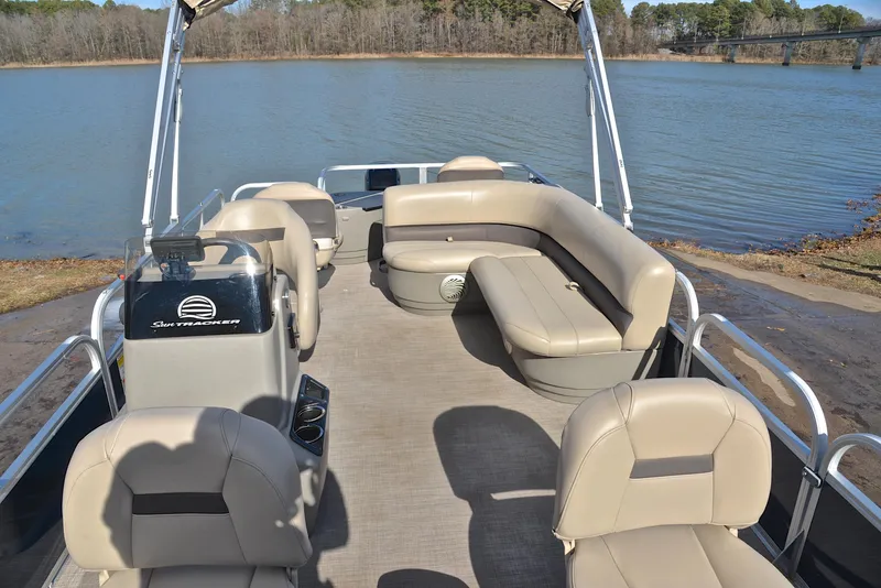 Slide: The Image of 2023 Sun Tracker Bass Buggy 18 DLX pontoon boat with beige seating on a lake. - 20