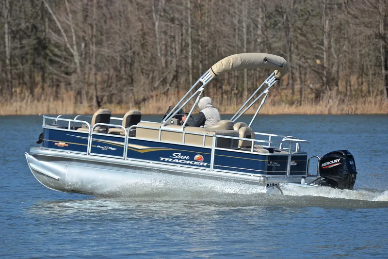 Slide: The Image of 2023 Sun Tracker Bass Buggy 18 DLX pontoon boat cruising on a lake. - 4