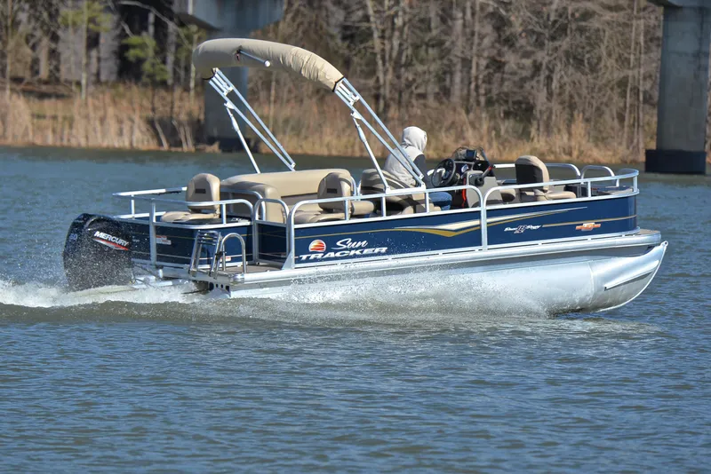Slide: The Image of 2023 Sun Tracker Bass Buggy 18 DLX pontoon boat cruising on a lake. - 5