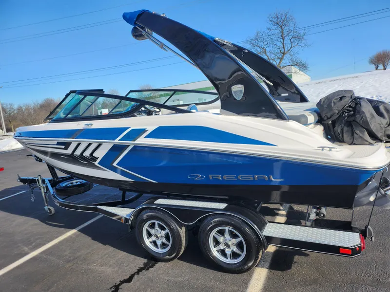 Slide: The Image of 2016 Regal 2000 ESX Bowrider on trailer, blue and white design, parked outdoors. - 4