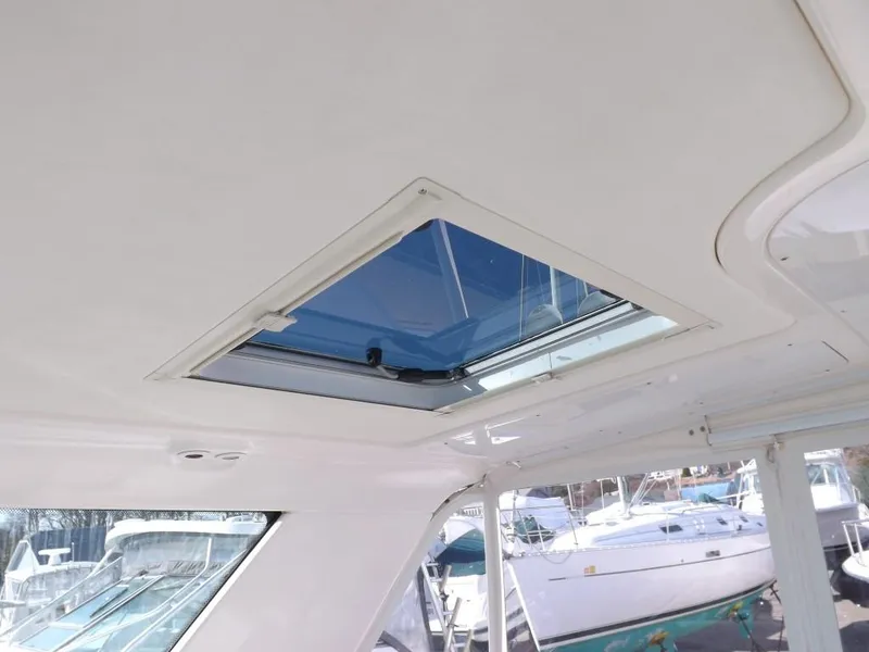 Slide: The Image of 2007 Tiara Yachts 3600 Sovran interior with open sunroof, docked boats visible outside. - 15