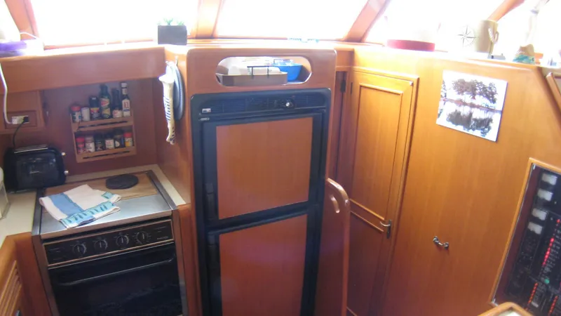 Slide: The Image of 2003 Ocean Alexander 423 Classicco yacht kitchen with wooden cabinetry, stove, and refrigerator. - 23