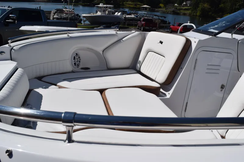 Slide: The Image of 2025 Stingray 211DC boat interior with white seating, docked by a lake. - 14